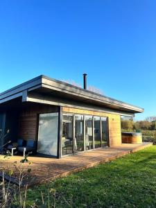 a house with a large wooden deck in a field at Eco Lodge "Deben" with Private Hot Tub in East Bergholt