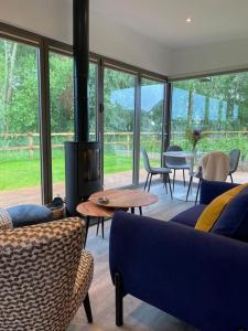 a living room with a couch and chairs and a fireplace at Eco Lodge "Deben" with Private Hot Tub in East Bergholt