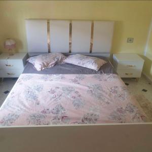 ein Bett mit einer rosa Decke und zwei Nachttischen in der Unterkunft appart près des ruines romaines in Sbeitla
