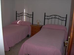 2 Betten in einem Zimmer mit rosa Bettwäsche in der Unterkunft La Kentia in Rincón de la Victoria