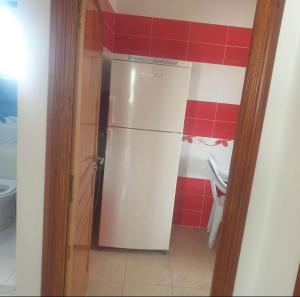 einen weißen Kühlschrank in einer Küche mit roten Fliesen in der Unterkunft appart près des ruines romaines in Sbeitla