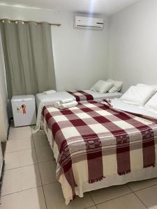 two beds in a room with a plaid blanket at Hotel Casa Blanca in Campina Grande