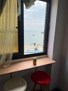 莒光鄉的住宿－台北人民宿，享有海滩美景的窗户,配有红色凳子