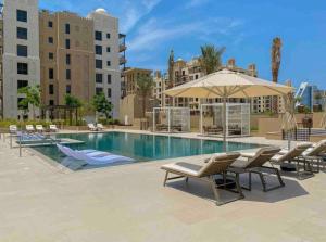 - une piscine avec des chaises longues et un parasol dans l'établissement Spacious 2 bedroom in Madinat Jumeirah Living, à Dubaï
