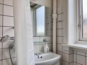 La salle de bains blanche est pourvue d'un lavabo et d'un miroir. dans l'établissement One Bedroom Apartment In Glostrup, Tranemosevej 1,, à Glostrup