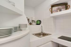 a white kitchen with a sink and plates on a counter at Sylvia's Villa in Imerovigli +36 photos