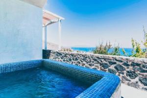 a blue tiled swimming pool next to a stone wall at Sylvia's Villa in Imerovigli