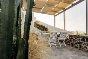 two chairs and a table on a patio with a cactus at Sylvia's Villa in Imerovigli
