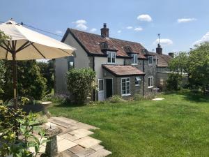 una casa con un paraguas en el patio en Charming modernized country cottage Near Mere, Wiltshire en Mere