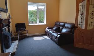 a living room with a leather couch and a window at Beech cottage 