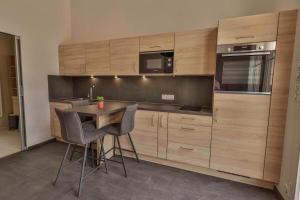 een keuken met houten kasten en een tafel en stoelen bij Domaine Grand Piquecaillou - L'appartement Loupiac 