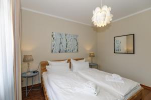 a bedroom with a bed with white sheets and a chandelier at Urlaubsräume am Meer Urlaubsräume am Meer 3-2 in Fulgen