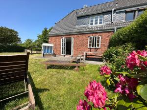 a house with a bench and flowers in the yard at Hüs am Seedeich in Westerland (Sylt)