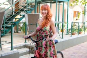 a woman in a dress sitting on a bike at Hunyadi Panzió-Apartman in Makó
