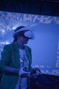 a woman wearing a hat is looking at a video game controller at Amenity Hotel & Resort Lipno in Lipno nad Vltavou