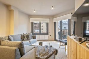 a living room with a couch and a tv at Luderna - Apartamento con terraza Montanero in Vielha