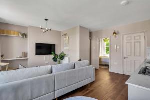 a living room with a gray couch and a kitchen at Be London - The St John's Wood Residences in London