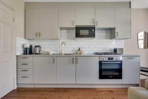 a white kitchen with white cabinets and appliances at Be London - The St John's Wood Residences in London