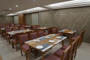 une salle à manger avec des tables et des chaises en bois dans l'établissement HOTEL STATURE INN, à Kevadia