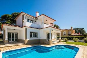 a villa with a swimming pool in front of a house at The Village – Praia D’El Rey Golf & Beach Resort in Casal da Lagoa Seca