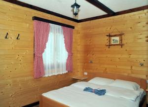una camera da letto con un letto in una stanza di legno di Milošev vajat - Miloš's cottage a Mionica