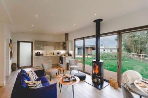 a living room with a blue couch and a fireplace at Beautiful "Stour" Eco Lodge with Private Hot Tub in East Bergholt