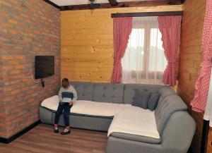 eine Person, die auf einer Couch mit einem Laptop sitzt in der Unterkunft Milošev vajat - Miloš's cottage in Mionica