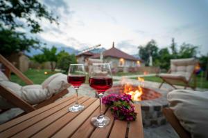 two glasses of wine on a wooden table with a fire pit at Kamkat Otel in Kemer