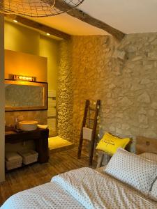 1 dormitorio con cama y pared de piedra en La chambre l'Eucalyptus en Saint-Laurent-du-Bois