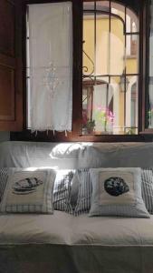 een witte bank met 2 kussens en een raam bij La Casa di Clo in Catania