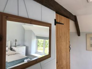 a mirror in a bedroom with a bed and a window at Charming modernized country cottage Near Mere, Wiltshire in Mere