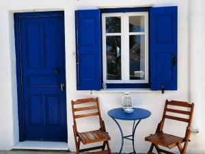 a table and two chairs and a blue door and window at Votsalo Apartments in Naousa