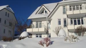 una casa blanca con nieve delante en Ferienwohnung der weite Blick mit Wellness, en Winterberg