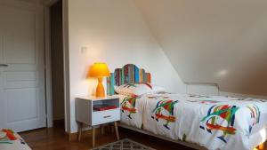 ein Schlafzimmer mit einem Bett und einer Lampe auf einem Nachttisch in der Unterkunft Le GITE DU VILLAGE in Franleu