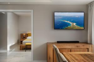 a living room with a television hanging on a wall at Hotel San Teodoro in San Teodoro
