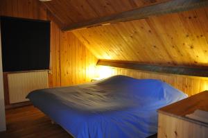 a bedroom with a blue bed in a wooden room at La Source du Broly in Soumagne