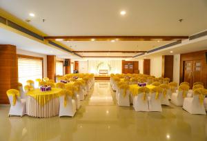 una sala banchetti con tavoli e sedie gialli e bianchi di HOTEL CEASAR PALACE a Kottayam