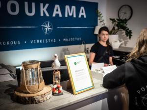a woman in an office with a counter with a table with a person in at Poukama in Porvoo