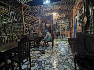 un homme assis à une table dans une pièce remplie de bouteilles de vin dans l'établissement Bamboo Nest, à Puerto Princesa