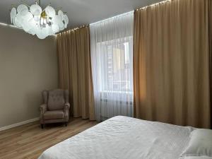 um quarto com uma cama, uma cadeira e uma janela em Квартира новая , 2 комн Исаева 71 em Oral