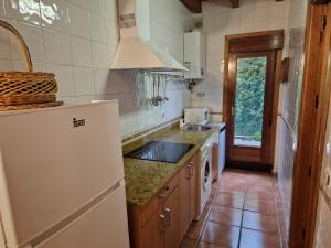 cocina con nevera blanca y fregadero en El Descanso de Sanabria, en Trefacio