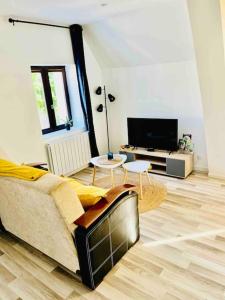 uma sala de estar com um sofá e uma televisão em La Perle em Montargis