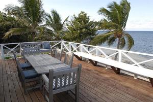a wooden deck with a table and benches on the beach at Castaway Cove by Grand Cayman Villas & Condos in Driftwood Village