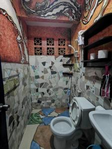 a bathroom with a toilet and a mosaic wall at Bamboo Nest in Puerto Princesa City