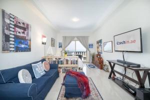ein Wohnzimmer mit einem blauen Sofa und einem TV in der Unterkunft Studio in Al Hamra Village with Sea View in Ras al Khaimah