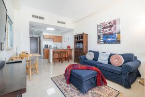 a living room with a blue couch and a kitchen at Studio in Al Hamra Village with Sea View in Ras al Khaimah