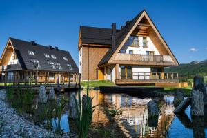 a house with a lake in front of it at Apartament Owca na wypasie by Apart Concept Podhale in Kościelisko