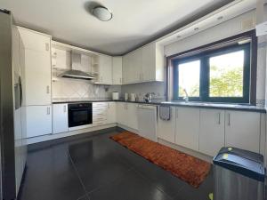 a kitchen with white cabinets and a window at Moradia praia de Esposende in Marinhas