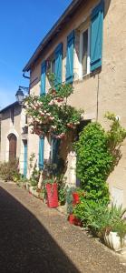 a building with blue windows and flowers in front of it at Chambre dans maison mosaïquée in Saint-Marcel