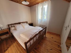 una camera da letto con un letto con lenzuola bianche e una finestra di Maison proche viaduc de Garabit a Loubaresse